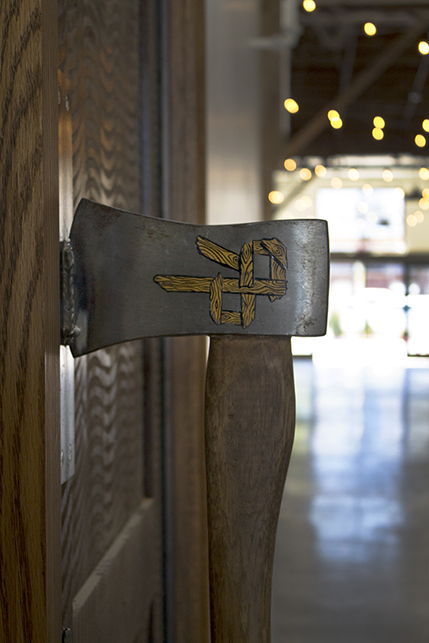 An antique woodcutter’s ax mounted on the large double doors acts as a handle and feature’s the River Pig logo
